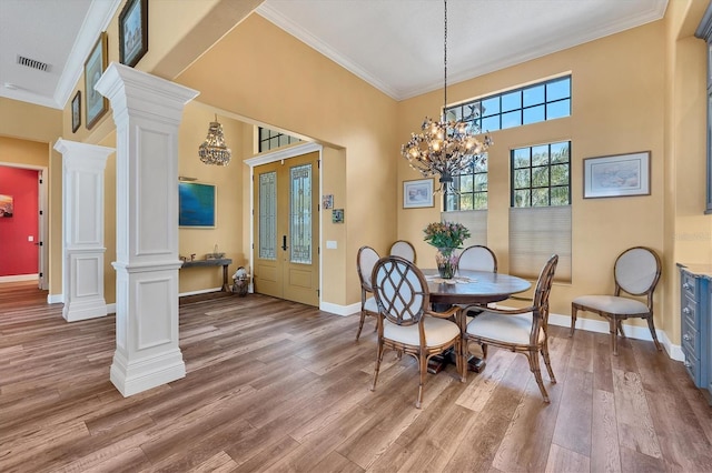 dining area featuring ornate columns, hardwood / wood-style flooring, ornamental molding, and a notable chandelier