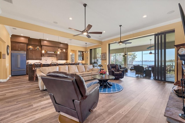 living room featuring crown molding, light hardwood / wood-style flooring, a water view, and ceiling fan