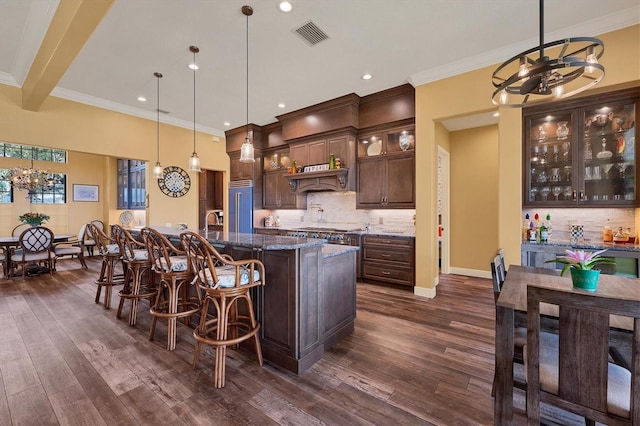 kitchen featuring dark brown cabinetry, an inviting chandelier, hanging light fixtures, and dark stone counters