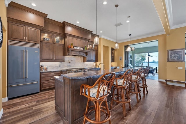 kitchen featuring a kitchen bar, decorative light fixtures, a large island, dark hardwood / wood-style flooring, and stainless steel appliances