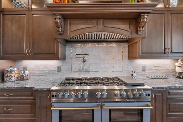 kitchen featuring double oven range, backsplash, and dark stone counters