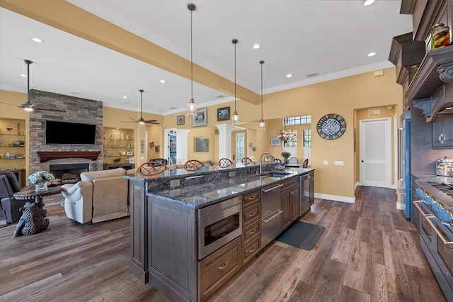 kitchen with high quality appliances, dark stone countertops, built in features, decorative light fixtures, and dark brown cabinetry