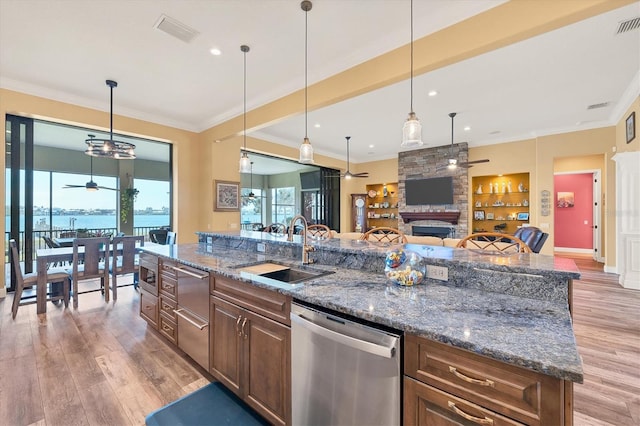 kitchen featuring sink, an island with sink, a fireplace, a water view, and appliances with stainless steel finishes