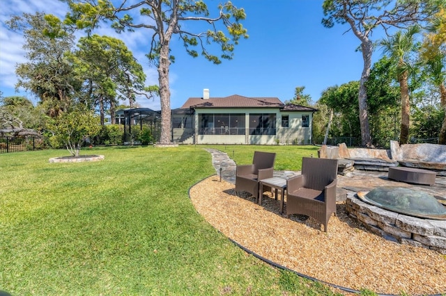 view of yard with fence, a sunroom, and a fire pit