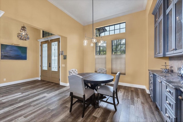 dining room with an inviting chandelier, ornamental molding, baseboards, a high ceiling, and dark wood-style floors