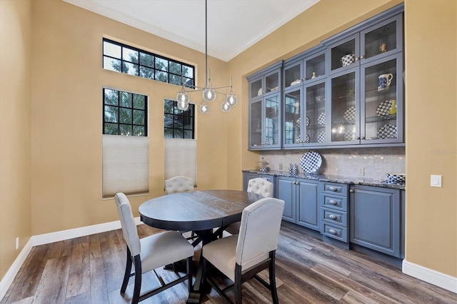 dining space featuring crown molding, baseboards, and dark wood-style flooring