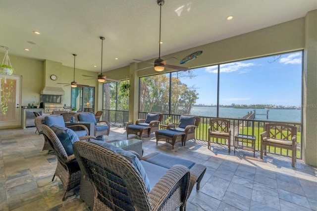 exterior space featuring a water view, exterior kitchen, outdoor lounge area, and ceiling fan
