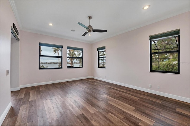 empty room featuring ornamental molding, dark wood finished floors, ceiling fan, and a wealth of natural light