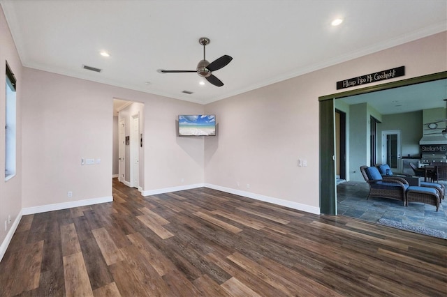 empty room with a ceiling fan, visible vents, wood finished floors, baseboards, and ornamental molding