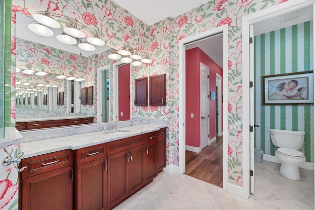 bathroom featuring vanity, baseboards, toilet, and wallpapered walls