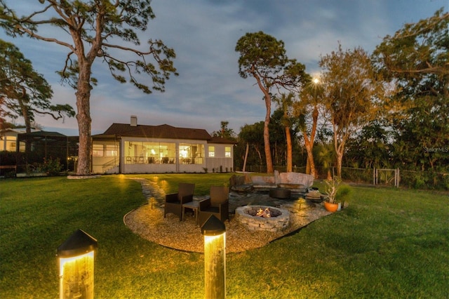yard at dusk with an outdoor fire pit and fence