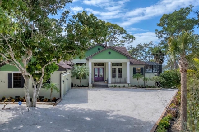 view of front of home featuring an attached garage, stucco siding, french doors, and driveway