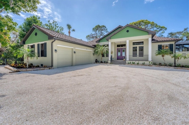 view of front facade with french doors, driveway, a tile roof, and a garage