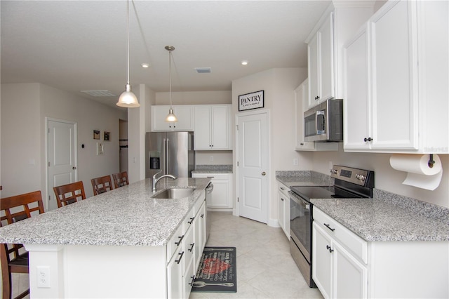 kitchen with sink, a breakfast bar area, a kitchen island with sink, white cabinets, and appliances with stainless steel finishes