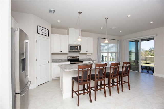 kitchen featuring light stone countertops, stainless steel appliances, a kitchen island with sink, white cabinets, and hanging light fixtures