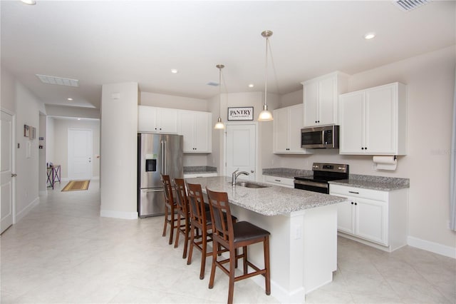 kitchen featuring white cabinetry, sink, a kitchen breakfast bar, a center island with sink, and appliances with stainless steel finishes