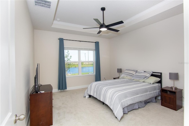 bedroom featuring ceiling fan, light carpet, and a tray ceiling