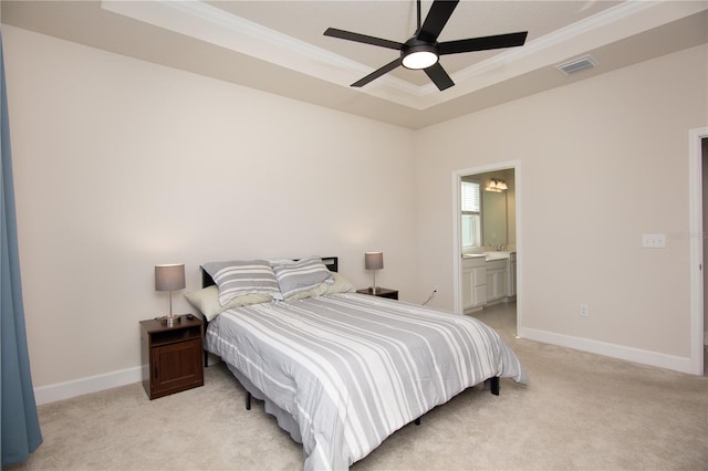 carpeted bedroom featuring a raised ceiling, ensuite bath, ceiling fan, and crown molding