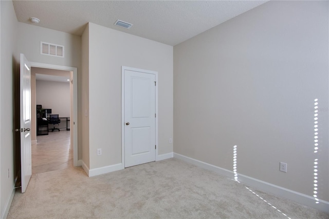 unfurnished bedroom with light carpet and a textured ceiling