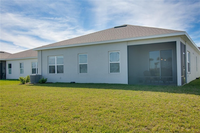 back of property with a lawn, a sunroom, and central AC unit