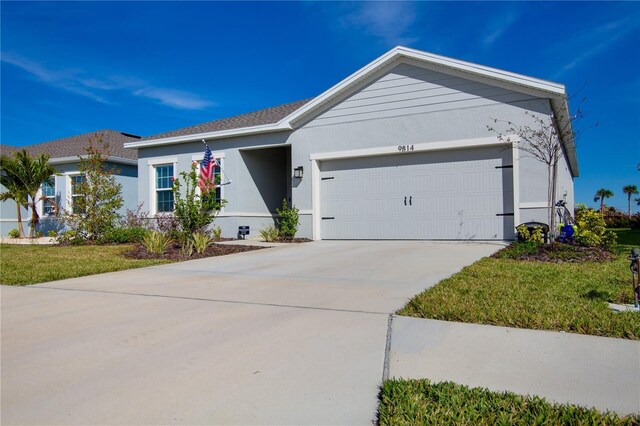 ranch-style home featuring an attached garage, a front lawn, concrete driveway, and stucco siding