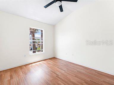 spare room with ceiling fan, vaulted ceiling, and wood finished floors