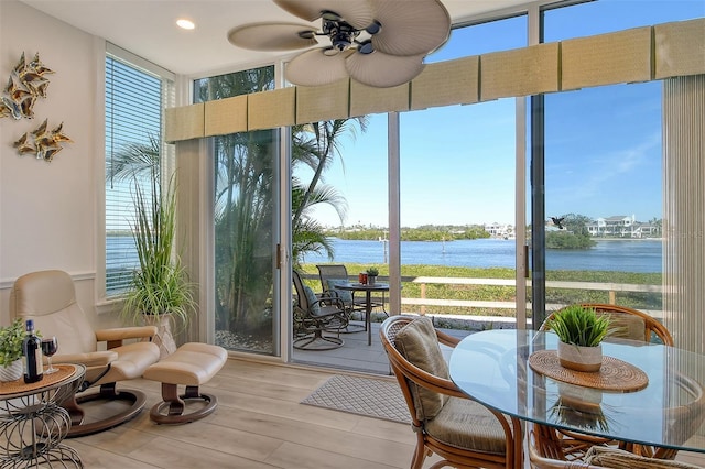 sunroom with a water view and ceiling fan