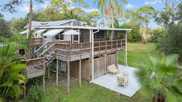 back of house featuring a sunroom, a patio area, a deck, and a yard