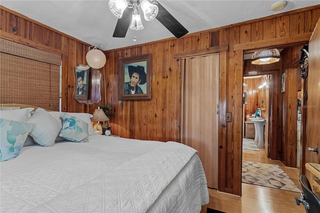 bedroom with ceiling fan, wood-type flooring, and wooden walls