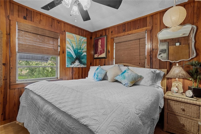 bedroom with ceiling fan and wooden walls