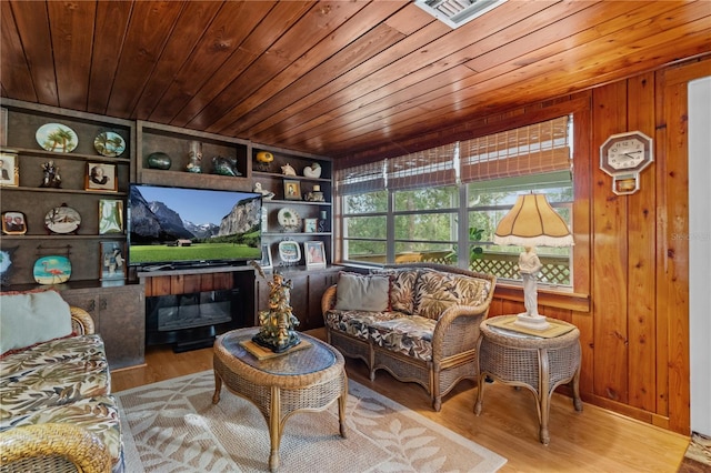 sitting room featuring wooden walls, light hardwood / wood-style flooring, wood ceiling, and built in features