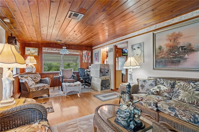 living room with light hardwood / wood-style floors, wood ceiling, and wooden walls