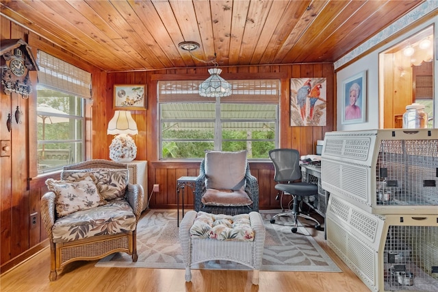 living area featuring a healthy amount of sunlight, light hardwood / wood-style flooring, wooden ceiling, and wood walls