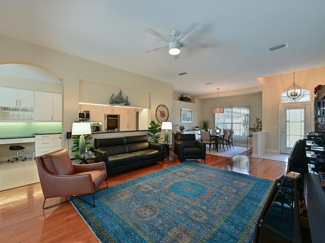 living room featuring light hardwood / wood-style floors and ceiling fan with notable chandelier