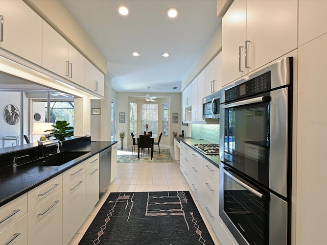 kitchen with backsplash, light tile patterned floors, a healthy amount of sunlight, white cabinetry, and stainless steel appliances