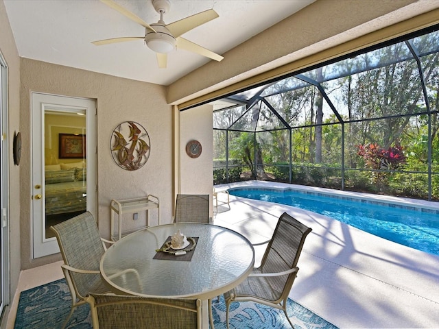 view of pool with ceiling fan, a patio area, and glass enclosure