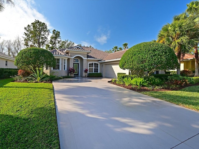 mediterranean / spanish house with a garage and a front lawn