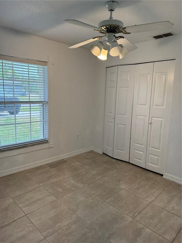 unfurnished bedroom featuring ceiling fan, light tile patterned floors, and a closet