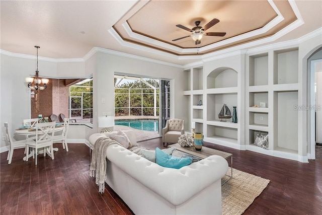 living room featuring ceiling fan with notable chandelier, a tray ceiling, dark hardwood / wood-style flooring, and crown molding