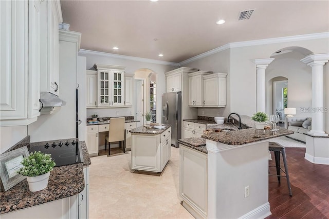 kitchen featuring stainless steel refrigerator with ice dispenser, a kitchen bar, white cabinets, and a center island