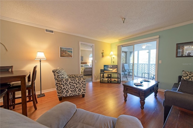 living room with hardwood / wood-style floors, ornamental molding, and a textured ceiling