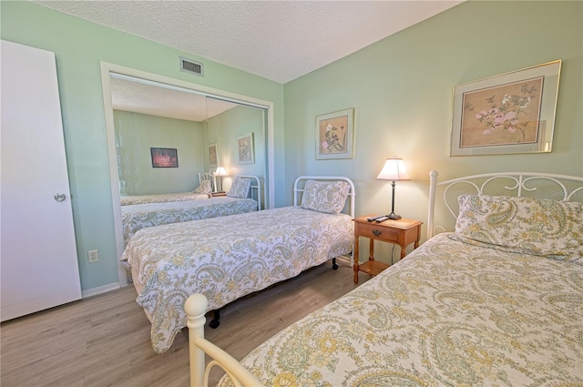 bedroom with wood-type flooring, a textured ceiling, and a closet