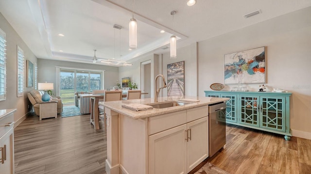 kitchen with a kitchen island with sink, sink, pendant lighting, light hardwood / wood-style flooring, and dishwasher