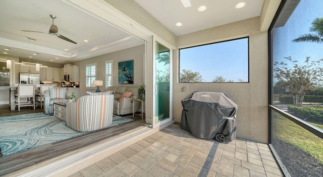 sunroom / solarium with ceiling fan and a tray ceiling