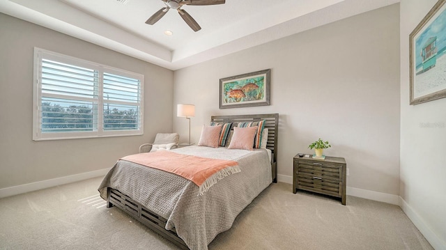 bedroom featuring light carpet, a raised ceiling, and ceiling fan