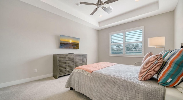 carpeted bedroom featuring a raised ceiling and ceiling fan