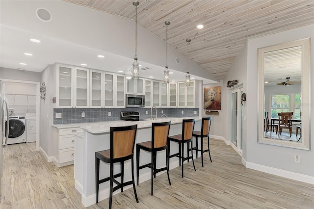 kitchen featuring wood ceiling, white cabinetry, stainless steel appliances, a center island with sink, and lofted ceiling