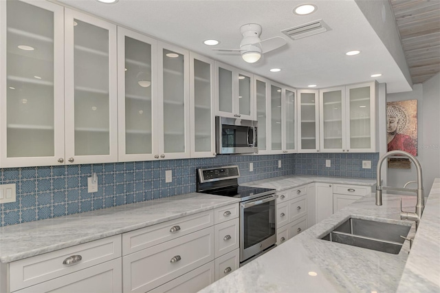 kitchen featuring light stone counters, sink, white cabinetry, and appliances with stainless steel finishes