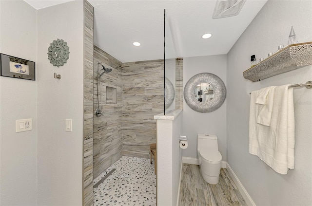 bathroom with tiled shower and toilet