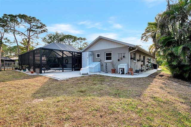 rear view of property featuring a lanai, a lawn, and a patio